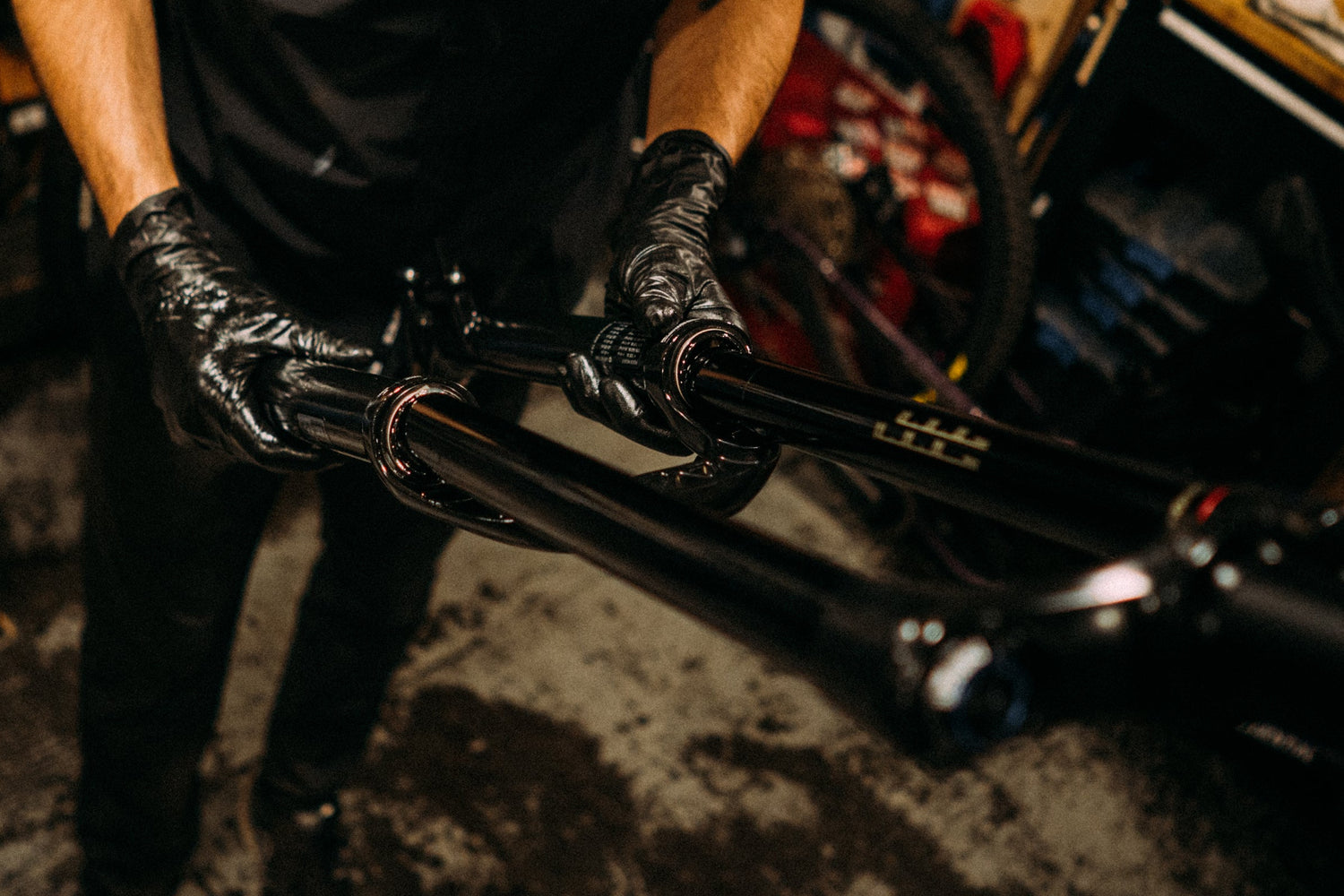 Person in a workshop putting suspension fork back together, surrounded by tools on a wall.