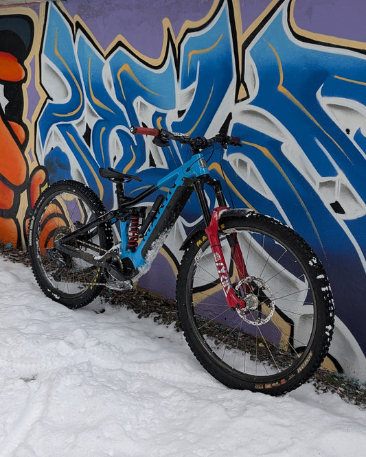 Bicycle leaning against a graffiti-covered wall with snow on the ground