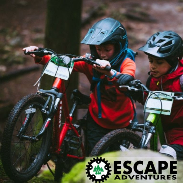 Two children on mountain bikes in a forest with 'Escape Adventures' logo.