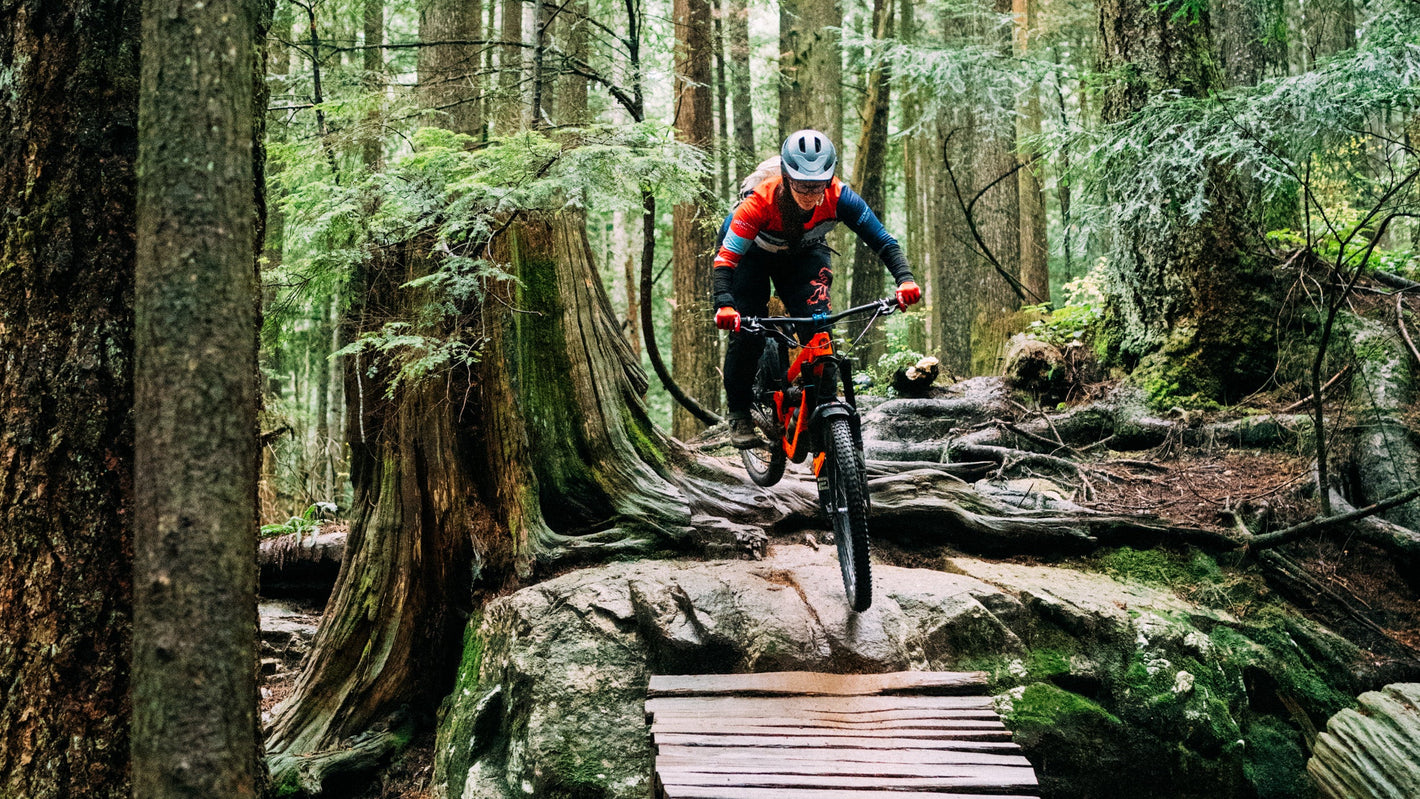 Person mountain biking over a wooden bridge in a forest