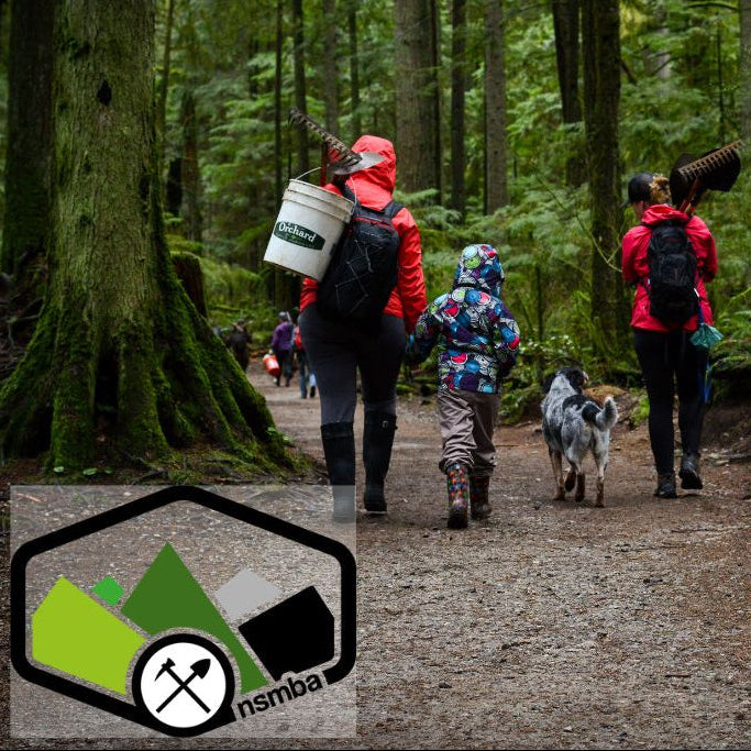 Group of people hiking with dogs in a forest, with NSMBA logo.